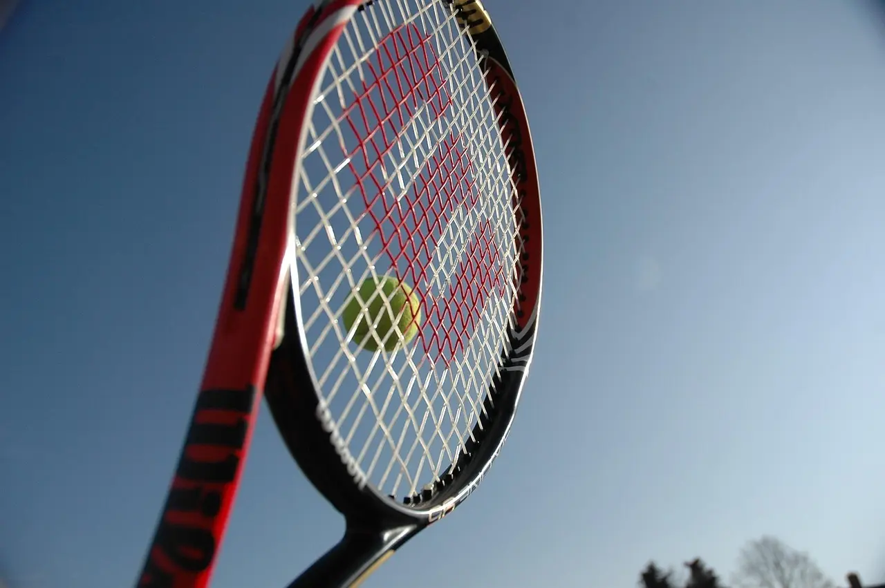 Tennisketsjer med tennisbold mod blå himmel